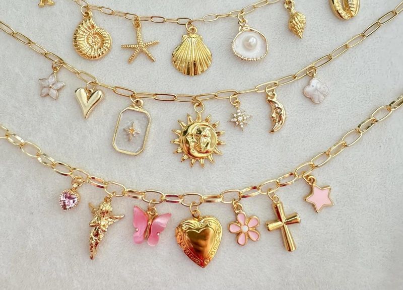 Close-up of a gold charm necklace with a heart locket, butterfly, flower and cross charms