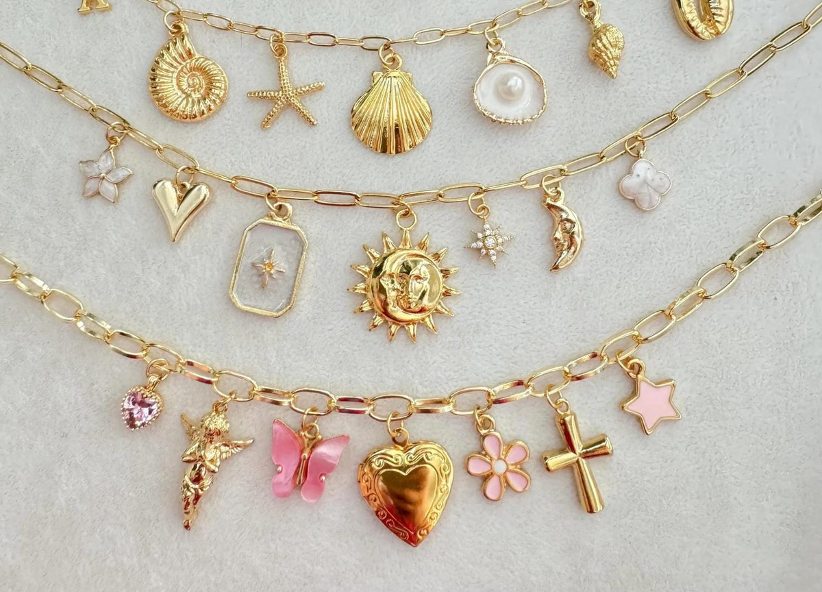 Close-up of a gold charm necklace with a heart locket, pink butterfly, flower, cross and angel charms