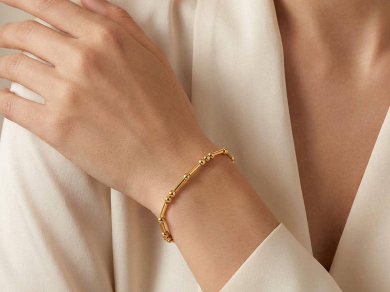 Hand wearing a delicate gold Morse code bracelet