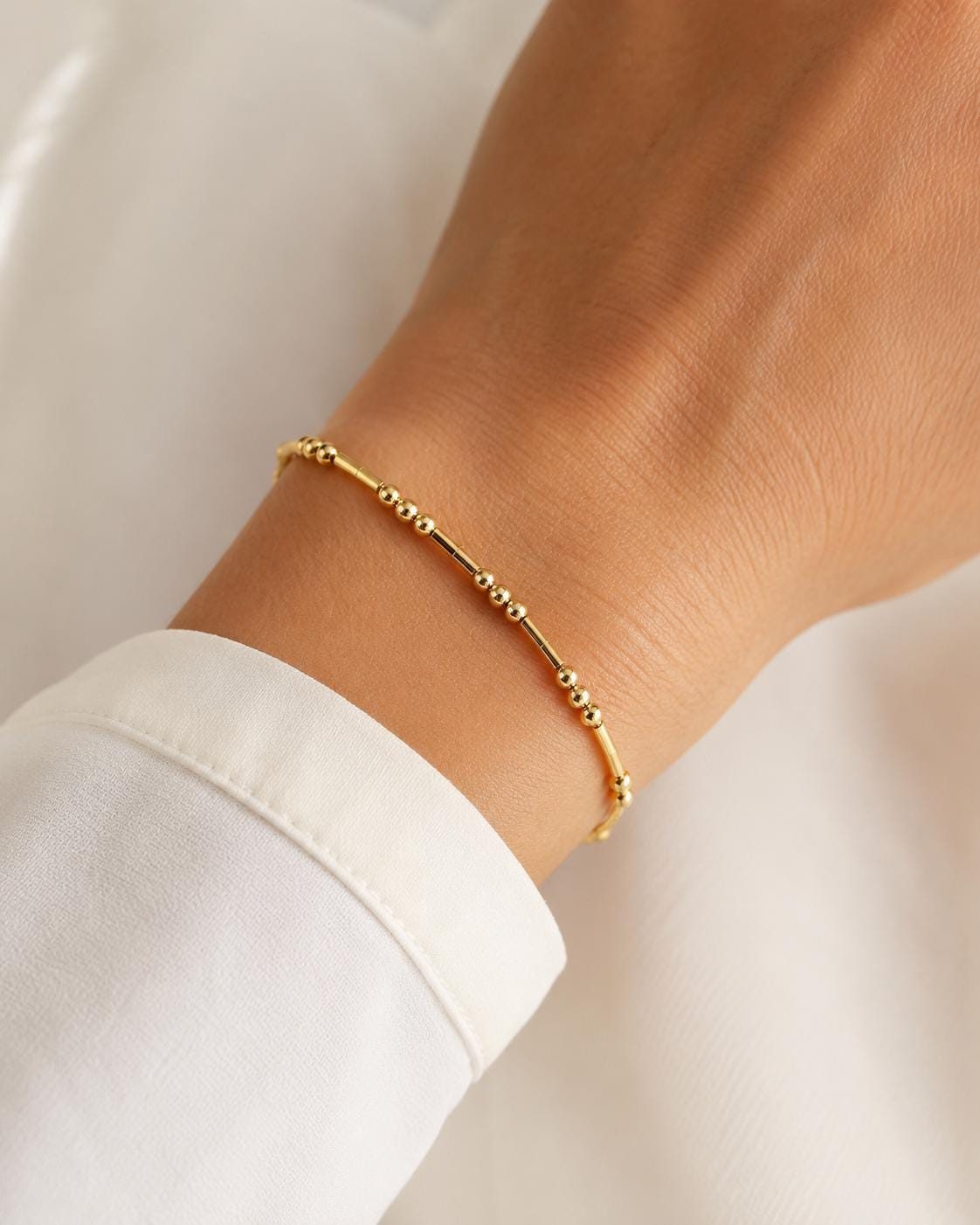 Gold Morse code bracelet worn on the wrist